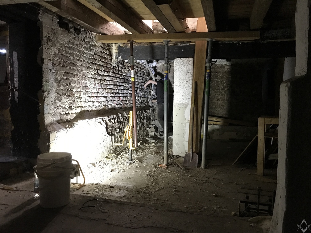 Entfernen von vermodertem Putz an der ersten Kellerwand im älteren Gebäudeabschnitt/Eingang Holzlager